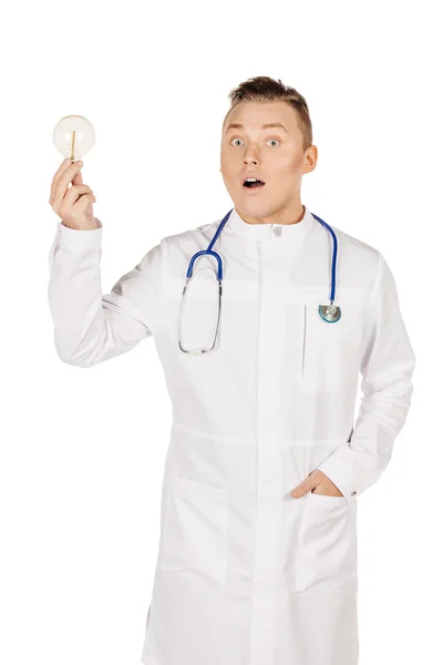 Young male doctor in white coat and stethoscope holding light bu — Stock Photo, Image