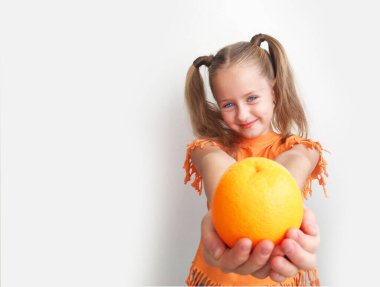 Kurabiyede taze portakal tutan bir kız. Kız beyaz arka planda duruyor. Şaşırdım