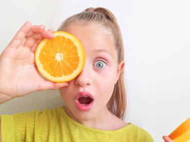 Kurabiyede taze portakal tutan bir kız. Kız beyaz arka planda duruyor. Şaşırdım