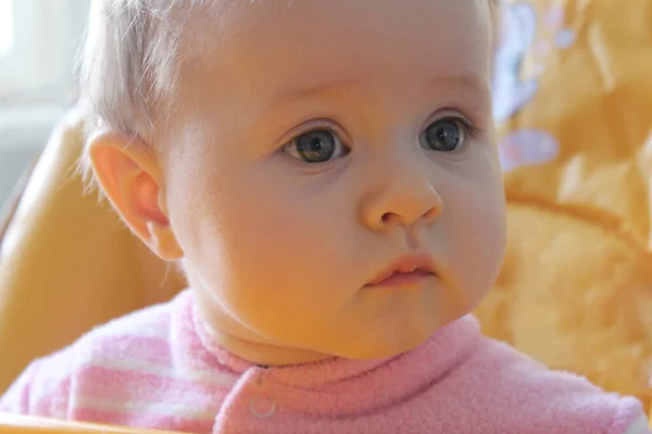 Baby En närbild söt liten blond 1-åring mot en suddig grön bakgrund. — Stockfoto