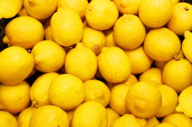 Limon, portakal, arka plan olarak taze meyve karışımı, üst manzara. Taze narenciye pazarı. Tahta bir masanın üstünde duran portakal yığını. 