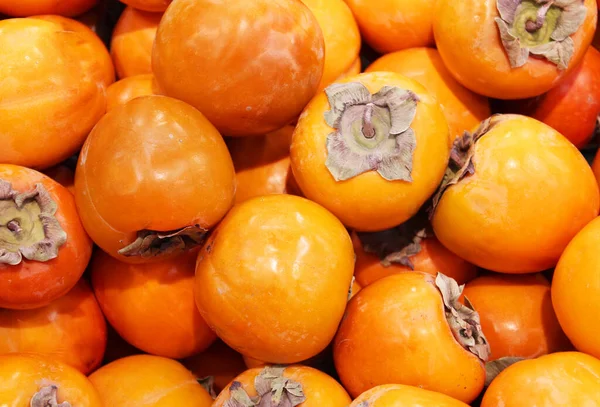 Olgun portakal hurmaları. Marketteki masada. Yerel bir çiftçi pazarında bir avuç organik hurma. Hurma arkaplanı. Düz yatıyordu. Metin ve içerik için alanı kopyala.