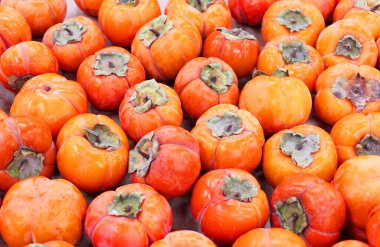 Olgun portakal hurmaları. Marketteki masada. Yerel bir çiftçi pazarında bir avuç organik hurma. Hurma arkaplanı. Düz yatıyordu. Metin ve içerik için alanı kopyala.