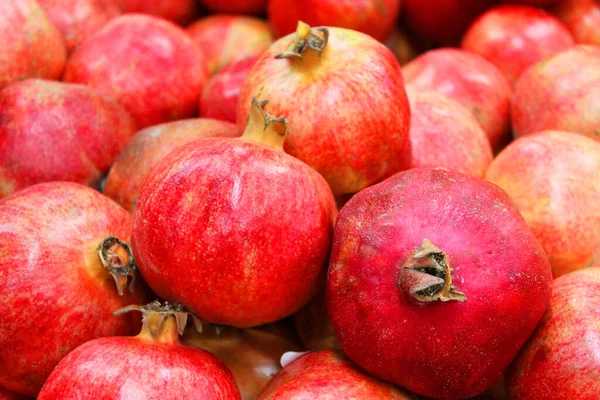 Pomegranate fruit background pattern. Whole pomegranate with flower. Fresh raw organic pomegranate fruit heap texture background. Ruby natural pomegranate close-up top view. on the market