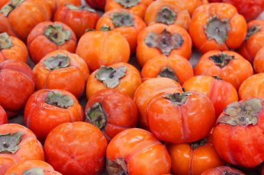 Olgun portakal hurmaları. Marketteki masada. Yerel bir çiftçi pazarında bir avuç organik hurma. Hurma arkaplanı. Düz yatıyordu. Metin ve içerik için alanı kopyala.