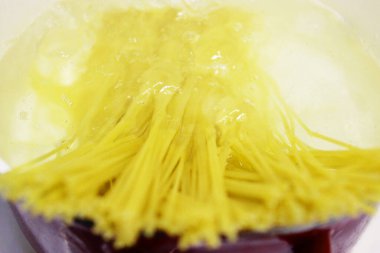 Mutfaktaki ocakta kaynar suyla tencerede makarna pişirmek. Makarna yapma süreci. Yaşam tarzı arka planı. Adamın biri kaynar suya spagetti atıyor. Yakın plan. Yatay olarak.