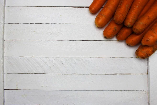 Величезна купа дуже великої свіжої і солодкої моркви на білому дерев'яному столі. красивий свіжий ринок органічної моркви у великій купі крупним планом повна рамка здорова їжа та фотографія здорового способу життя — стокове фото