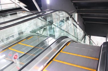 Alışveriş merkezinin metal kazıcısında merdivenleri olan modern lüks yürüyen merdivenler lastik parmaklıklı neon ışıklı, merdiven manzaralı, zemine inen.. Günlük hayatta güvenliğin farkındalığı Modern