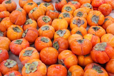 Olgun portakal hurmaları. Marketteki masada. Yerel bir çiftçi pazarında bir avuç organik hurma. Hurma arkaplanı. Düz yatıyordu. Metin ve içerik için alanı kopyala.