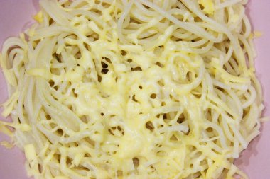 Makarna, pembe bir kasede makarna, beyaz peynirli eski ve eski bir ahşap masa. Akşam yemeği için hazırlanmış peynirli bir tabak lezzetli makarna. Yaklaştın. Fotokopi alanı. yatay