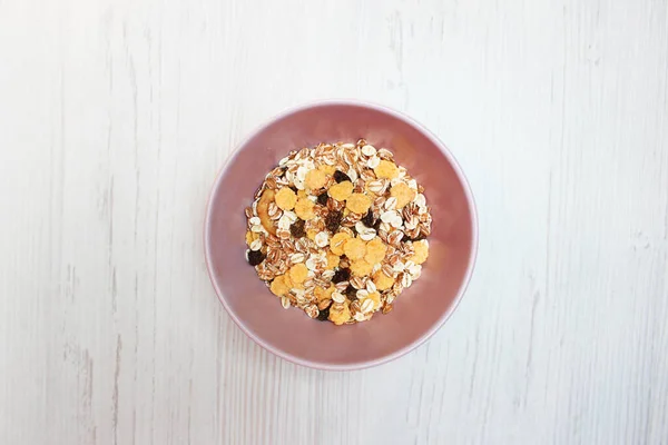Pembe tabakta müsli, üst manzara. Müsli, taze süt, yoğurt ya da kefir. Müsli yulaf ezmesinden, kurutulmuş meyve, fındık ve ayçiçeği tohumlarının karışımından yapılır. Beyaz üzerine.