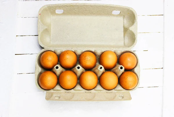 Karton bir kutuda kahverengi yumurtalar. Kutuda taze organik tavuk yumurtaları ya da yumurta kabı. Beyaz ahşap arka planda yumurta içinde çiğ tavuk yumurtalarının yakın görüntüsü. Tavuk yumurtalı kutu.