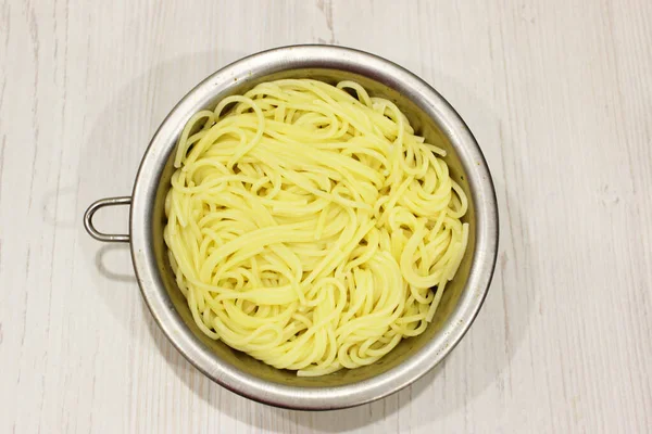 Makaron, spaghetti w metalowym dushlog na starym i zabytkowym drewnianym stole. podawane gotowe na obiad. Zamknięte. z przestrzenią kopiowania. poziomy — Zdjęcie stockowe