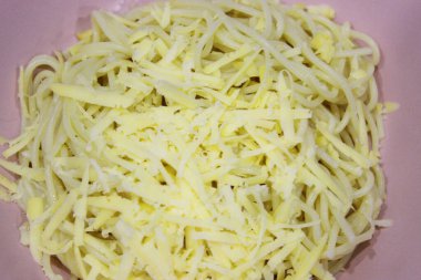 Makarna, pembe bir kasede makarna, beyaz peynirli eski ve eski bir ahşap masa. Akşam yemeği için hazırlanmış peynirli bir tabak lezzetli makarna. Yaklaştın. Fotokopi alanı. yatay