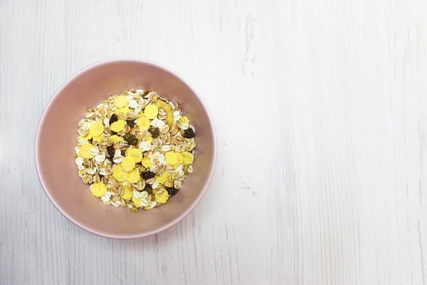 Pembe tabakta müsli, üst manzara. Müsli, taze süt, yoğurt ya da kefir. Müsli yulaf ezmesinden, kurutulmuş meyve, fındık ve ayçiçeği tohumlarının karışımından yapılır. Beyaz üzerine.