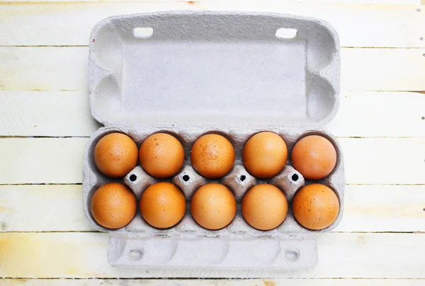 Karton bir kutuda kahverengi yumurtalar. Kutuda taze organik tavuk yumurtaları ya da yumurta kabı. Beyaz ahşap arka planda yumurta içinde çiğ tavuk yumurtalarının yakın görüntüsü. Tavuk yumurtalı kutu.