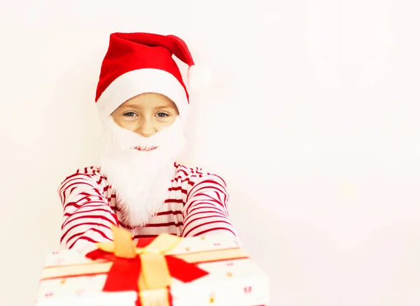 Święty Mikołaj daje prezenty do kwarantanny na czerwony sweter Boże Narodzenie i Nowy Rok prezent. Happy little girl w Santa s kapelusz ma Boże Narodzenie. — Zdjęcie stockowe