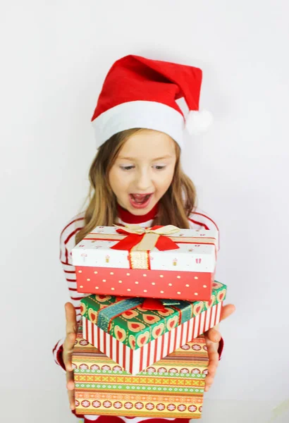 Güzel kız kırmızı kazağı Noel ve yeni yıl hediyesi. Noel Baba şapkalı mutlu küçük kız Noel 'i kutlar.