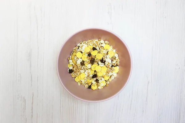 Pembe tabakta müsli, üst manzara. Müsli, taze süt, yoğurt ya da kefir. Müsli yulaf ezmesinden, kurutulmuş meyve, fındık ve ayçiçeği tohumlarının karışımından yapılır. Beyaz üzerine.
