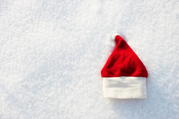 Red Santa hat and knitted mittens lie on the snow. mitten lying on the snow in winter. Holiday Decorations Christmas and New Year Traditions Panoramic Banner Free Space Text Top View Flst lay — Stock Photo, Image