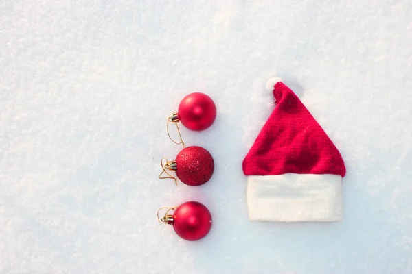 Santa Claus hatt jul bakgrund med färgade julbollar, julleksaker, bollar, dekorationer på en vit snö bakgrund God jul tema vintersemester. i snön med mild boke — Stockfoto