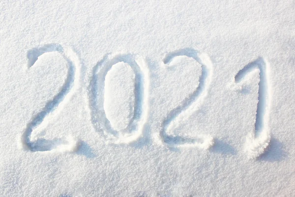 Feliz año nuevo 2021 texto signo escrito con números de nieve en la superficie de la nieve, símbolo del próximo año marcado sobre un fondo de invierno nevado. Inscripción 2021 en una deriva de nieve a la luz del sol. Año nuevo —  Fotos de Stock