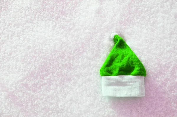 Chapéu de Papai Noel verde e luvas de malha jazem na neve. mitten deitado na neve no inverno. Decorações de Férias Tradições de Natal e Ano Novo Bandeira Panorâmica Espaço Livre Texto Top View Flst lay — Fotografia de Stock