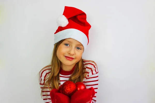 Der kleine Weihnachtsmann beschenkt mit rotem Pullover Weihnachten und Neujahr. Das fröhliche kleine Mädchen mit Weihnachtsmütze hat Weihnachten — Stockfoto