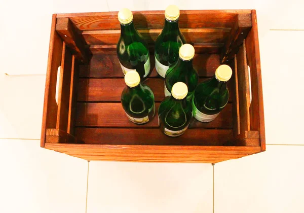 Bottiglie di vino in una scatola vicino. Scatola con bottiglie di bevanda in una scatola di legno su uno sfondo di legno bianco. Con spazio per la copia. Esperienza vino. Il concetto di vacanza, festa, celebrazione. negozio di bevande — Foto Stock