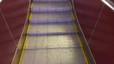 Modern lüks yürüyen merdivenler. Hareket eden kazıcı adımlarının videosu değişiyor. Bir alışveriş merkezindeki merdiven kazıcıyla plastik parmaklıklı neon ışıklı, merdiven manzaralı, zemine inen.