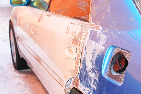 On the street, damaged blue car after a collision in the city. The car body is damaged as a result of an accident. The car is being repaired. instead of rear lights, bulbs stick out, traces of paint — Stock Photo, Image