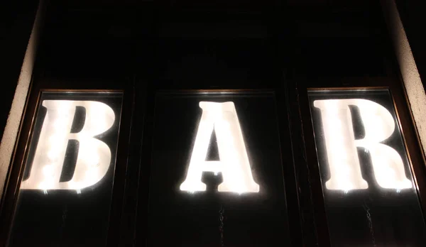 Alphabet letters in vintage style with glowing bulbs inside. Backlit marquee letters illuminated marquee letters name of the bar. — Stock Photo, Image