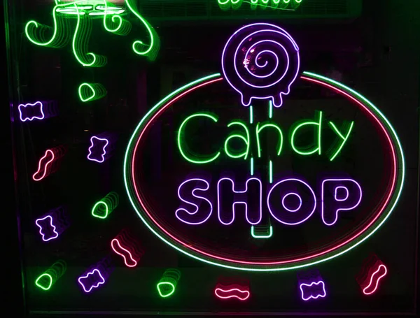 Letras de neón Caramelo tienda con iluminación de neón en el vidrio, el concepto de un café y café, y dulces Brillante letras de neón y estilizado,. Imagen vintage en tonos oscuros. — Foto de Stock