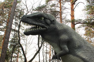 Dinozor figürü heykeller. Model dinozor yosunlu bir kayanın önünde duruyor. Yakından, gerçek boyutlarda büyük bir dinozor.