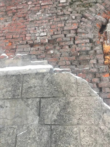 Antigua casa en ruinas en la ciudad, gran ventana antigua, ventanas sucias, decoración colapsada, yeso de ladrillo viejo visible, metal oxidado. Un edificio gris sombrío en el centro de la ciudad necesita renovación y —  Fotos de Stock