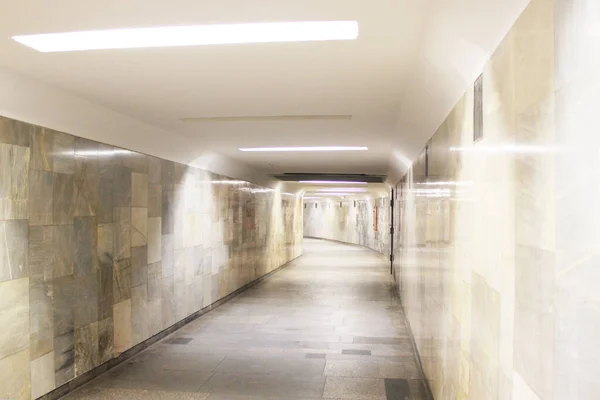 A long empty tunnel leads in the distance. Pedestrian crossing in the metro from one station to another, walls are made of light marble. Subway tunnel track without people. Public transport — Stock Photo, Image