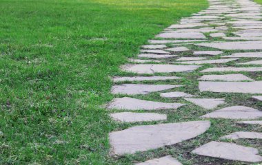 Gri asfalt levhalar, asfalt yollar, gölgeli bir parktaki yeşilliklerin arasında. Yüzeyin derinliği Paving levhaları. Yolda küçük tuğlalar var. Kirli, ıslak kaldırım. Geçmişi. Yol işaretleri, kaldırımlarda yosun.