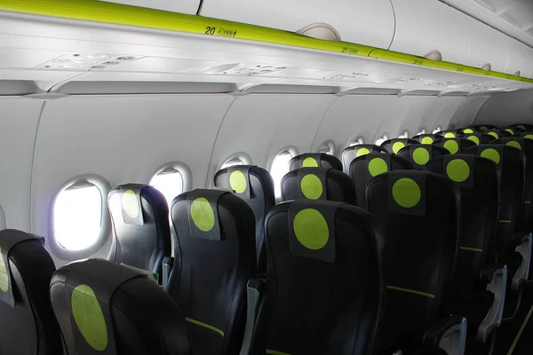 aircraft cabin, seats, portholes, empty plane without passengers. Rows of gray leather seats and windows in the aisle of the plane. Economy class aircraft seats. Background, copy space, close-up