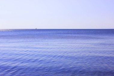 Açık mavi gökyüzü ile deniz ufku. Yüksek kalite fotoğraf. Yatın mavi denizde yelken açmasına odaklan. Denizde dinlenen bir gemi ve denizdeki adalar..