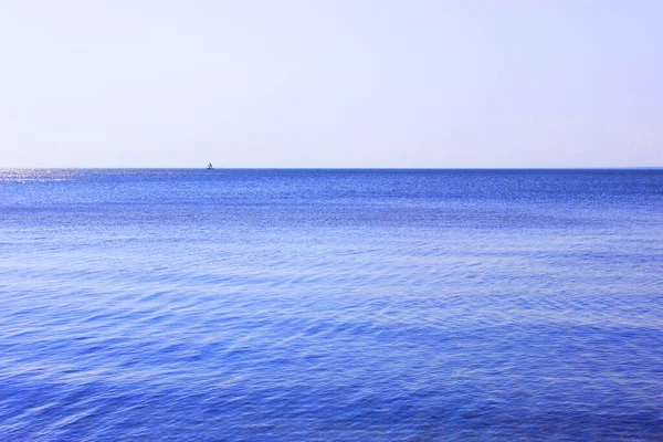 Açık mavi gökyüzü ile deniz ufku. Yüksek kalite fotoğraf. Yatın mavi denizde yelken açmasına odaklan. Denizde dinlenen bir gemi ve denizdeki adalar..