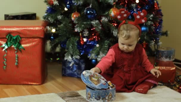 Niño con caja de caramelos al lado de un árbol de Navidad — Vídeo de stock