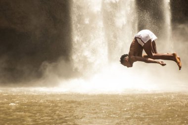 Genç adam Ouzoud Şelalesi 'ndeki bir uçurumdan suya atlıyor.