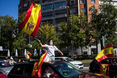 Genç bir kadın İspanyol Babalar Günü 'nde VOX gösterisinde bir arabadan İspanyol bayrağı sallıyor.