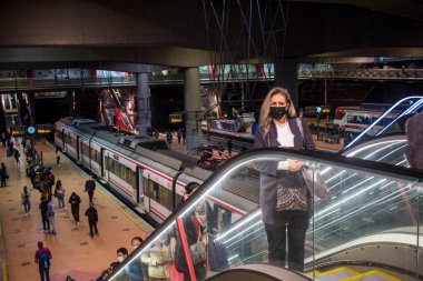 Madrid 'deki RENFE banliyö trenlerinin Atocha istasyonundaki kalabalık, Coronavirus salgınından dolayı günlük yolculuklarını yapıyor, maske takarak yürüyen merdivenleri tırmanıyor.