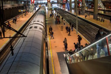Madrid 'deki RENFE banliyö trenlerinin Atocha istasyonundaki kalabalık, Coronavirus salgınından dolayı günlük yolculuklarını yapıyor, maske takarak yürüyen merdivenleri tırmanıyor.