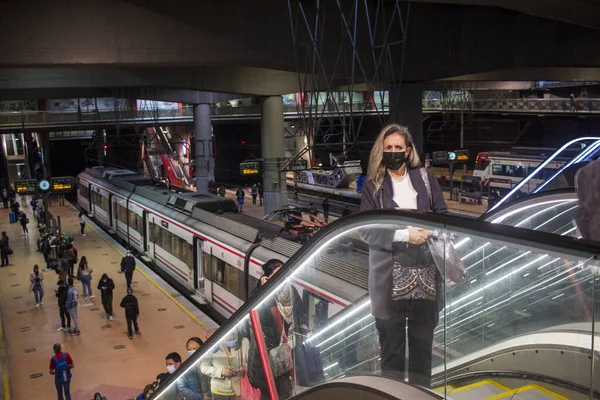 Madrid 'deki RENFE banliyö trenlerinin Atocha istasyonundaki kalabalık, Coronavirus salgınından dolayı günlük yolculuklarını yapıyor, maske takarak yürüyen merdivenleri tırmanıyor.