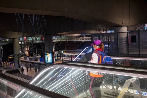 Madrid 'deki RENFE banliyö trenlerinin Atocha istasyonundaki kalabalık, Coronavirus salgınından dolayı günlük yolculuklarını yapıyor, maske takarak yürüyen merdivenleri tırmanıyor.