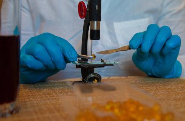 Mavi laboratuarda mikroskop ve eller eldiven takın.