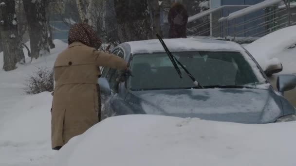 Limpiando el coche de la nieve en invierno en el frío y la nieve — Vídeos de Stock