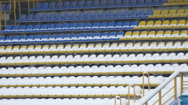 Cadeiras azuis amarelas cobertas com estádio de neve — Vídeo de Stock